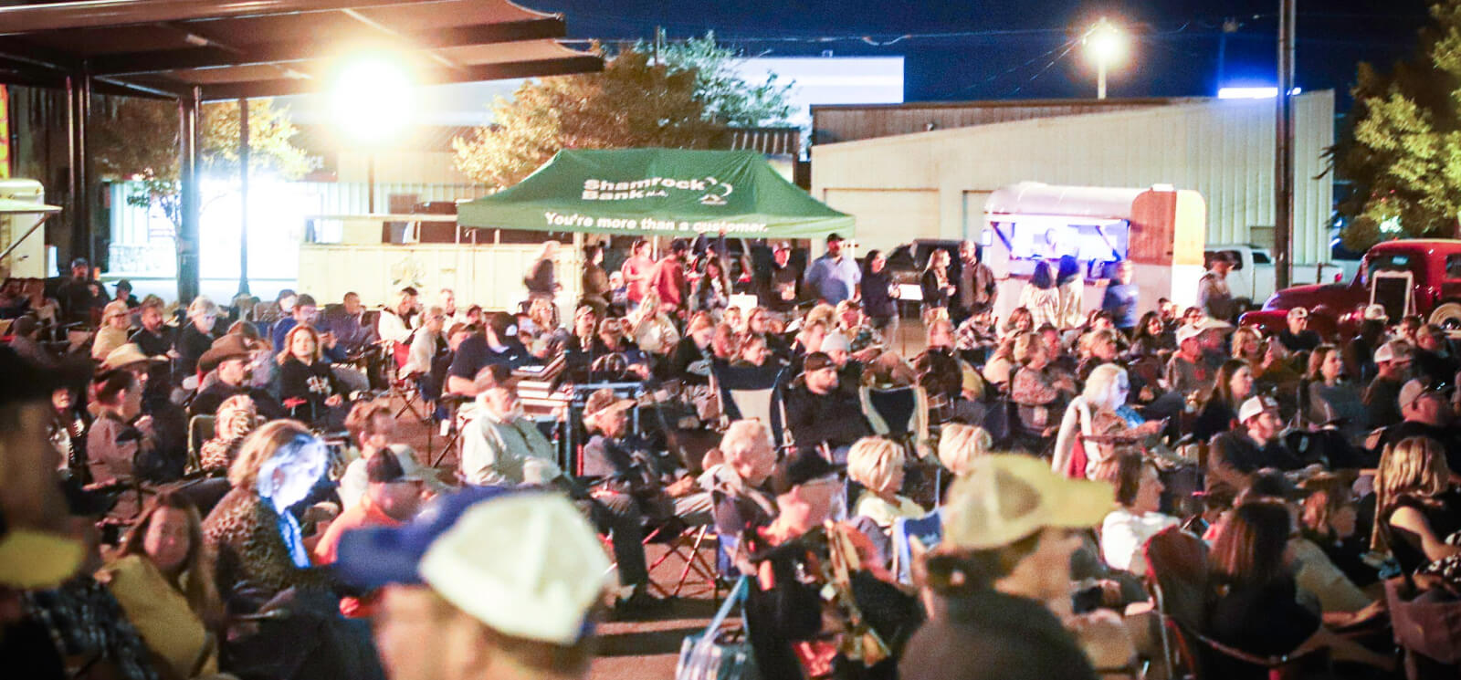 Community members at an evening event with a Shamrock Bank tent