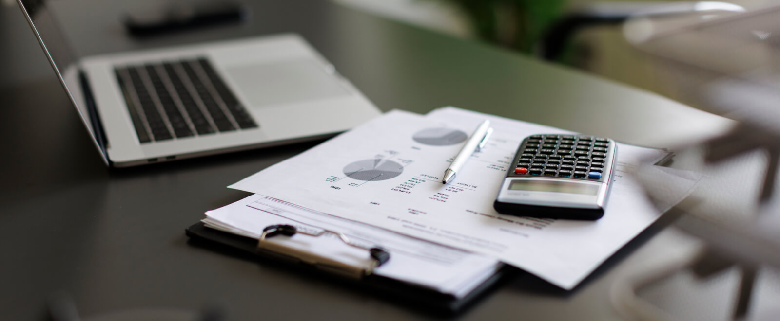 calculator, papers, and laptop on desk